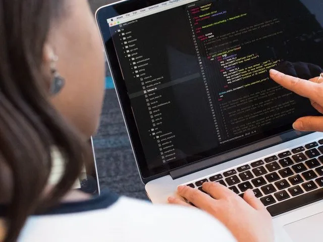 Fejlesztőcsapat közösen egyeztet egy weboldal kódján párban dolgozva